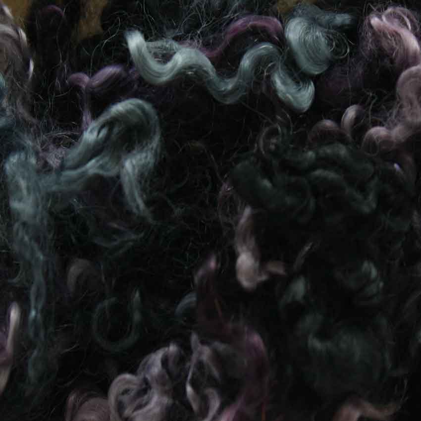 Close up of evening mohair curls showing shades of dark blue, lavender, soot