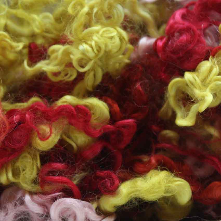 Close up of fireworks mohair curls showing shades of red, yellow and pink