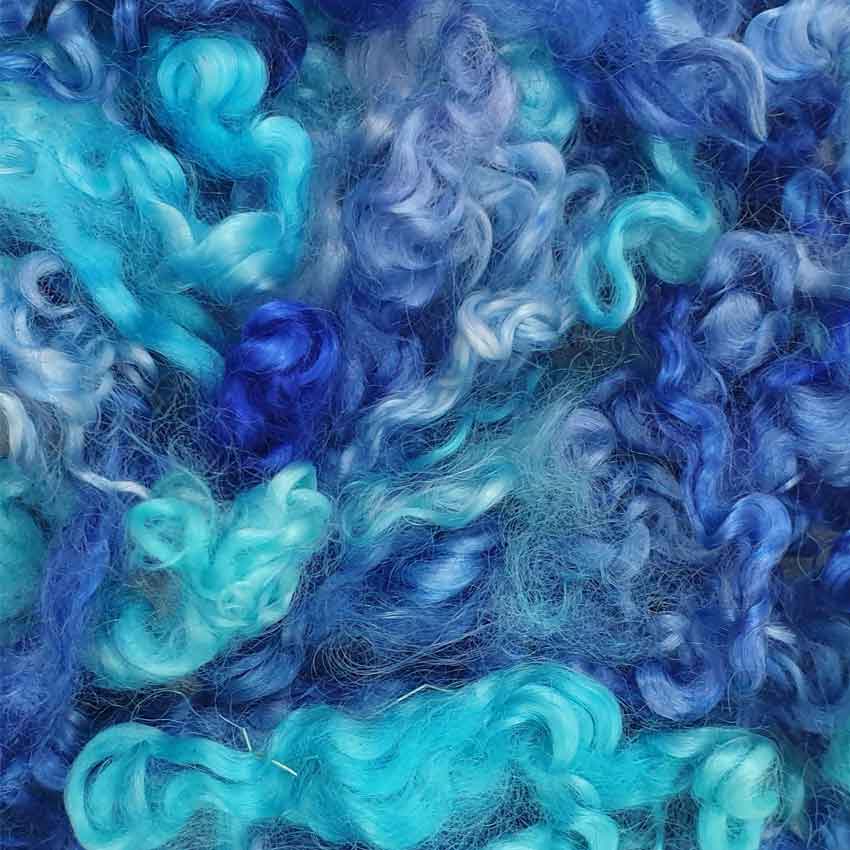 Close up of blue hues mohair curls showing varying shades of blue